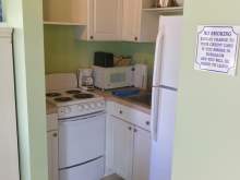 Green kitchen with white cabinets, sink, microwave, refrigerator