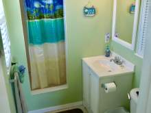 Bathroom with green wall, shower with decorative curtain, sink, toilet
