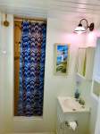 Bathroom shower with blue and white curtain, white walls, sink, lighthouse image