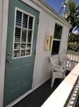 Outdoor deck, white exterior, blue door, two chairs, deck railing