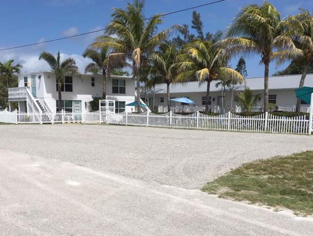 Seahorse Beach Bungalows parking lot, two story apartment style building with palm trees, picket fence