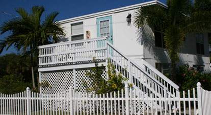 Two-story white building with exterior stairs going to upstairs bungalow, white picket fence